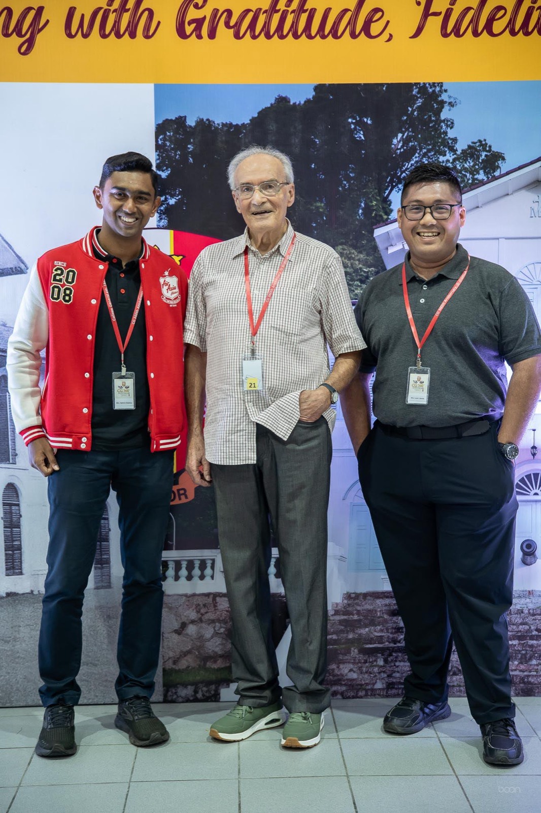 A senior priest with two younger alumni before the CG 360 backdrop