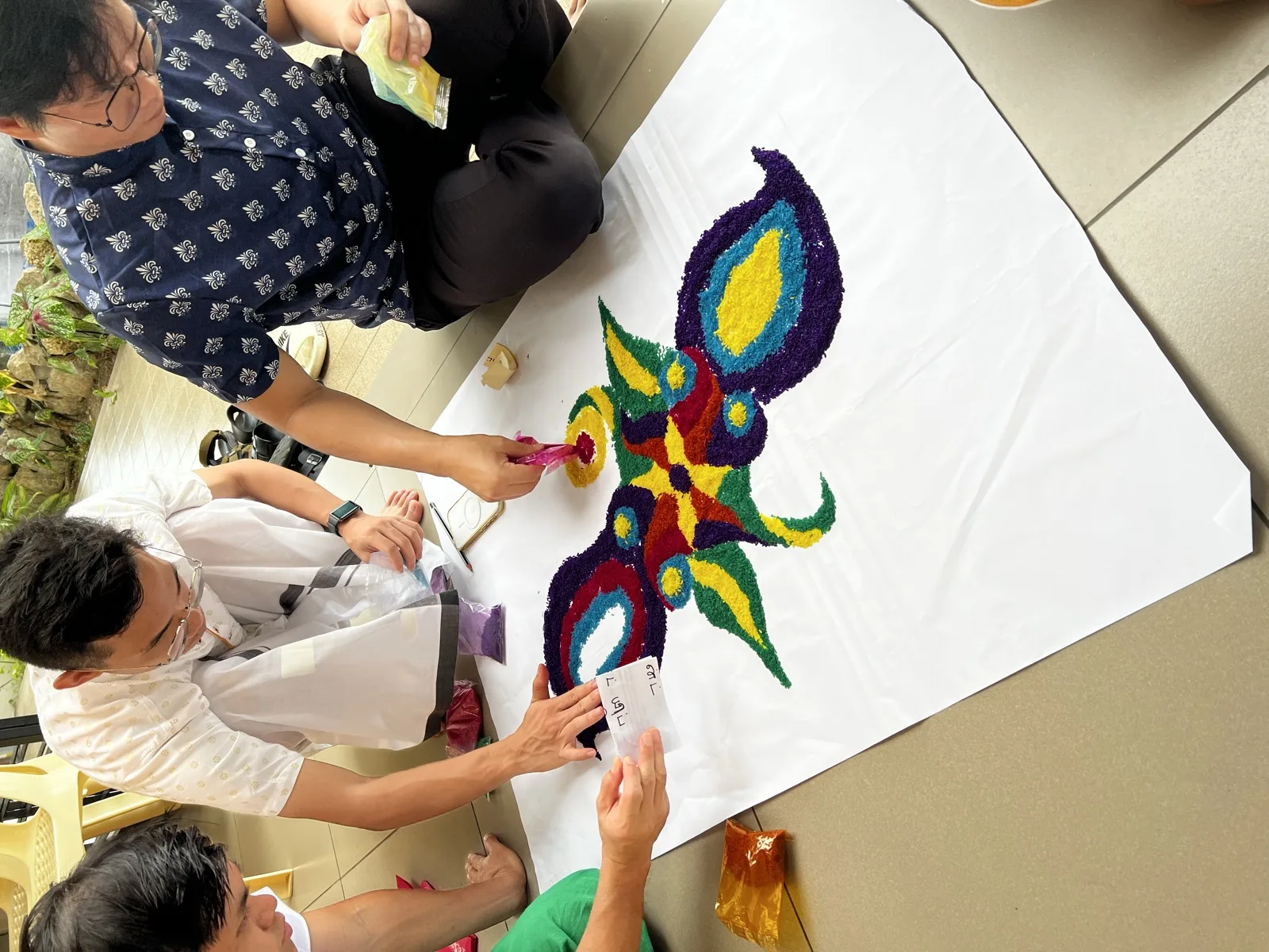 A kolam being drawn by hand for a community celebration